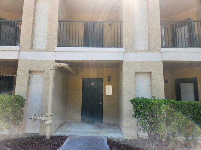 entrance to property with stucco siding and a balcony
