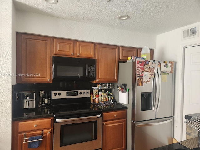kitchen featuring a textured ceiling, brown cabinets, dark countertops, and stainless steel appliances