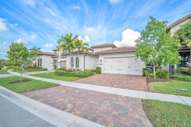 mediterranean / spanish-style house featuring stucco siding, an attached garage, decorative driveway, and a tile roof