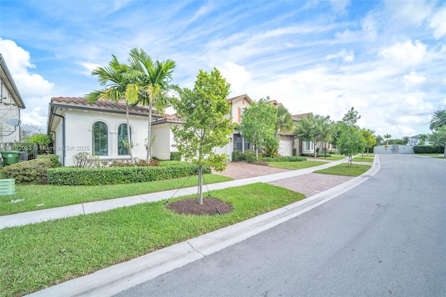 mediterranean / spanish-style home with decorative driveway, a front yard, and stucco siding