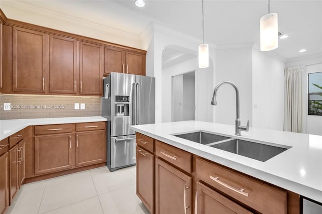 kitchen with a sink, brown cabinets, ornamental molding, and stainless steel refrigerator with ice dispenser