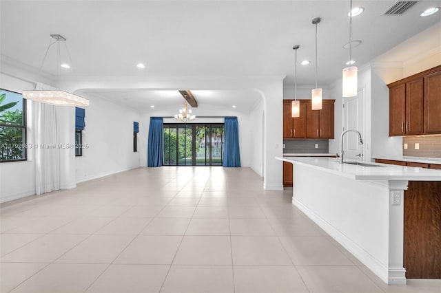 kitchen with a sink, light countertops, decorative backsplash, and visible vents
