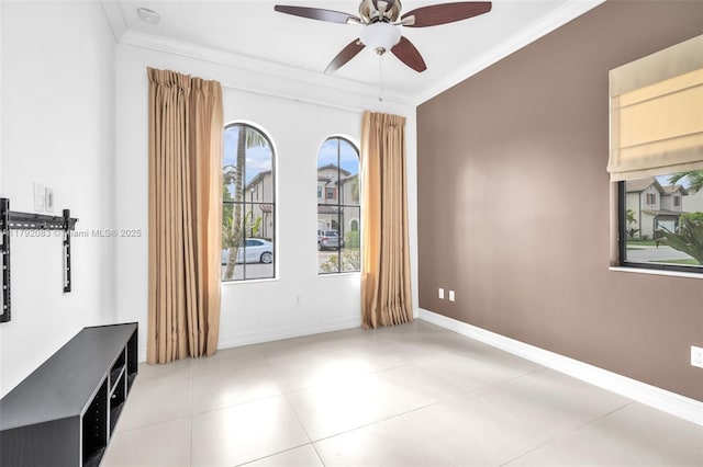 spare room featuring crown molding, a ceiling fan, baseboards, and light tile patterned flooring