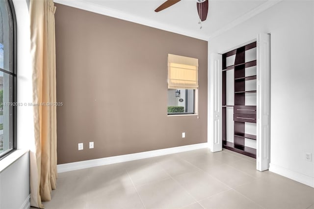 empty room with crown molding, baseboards, ceiling fan, and tile patterned floors