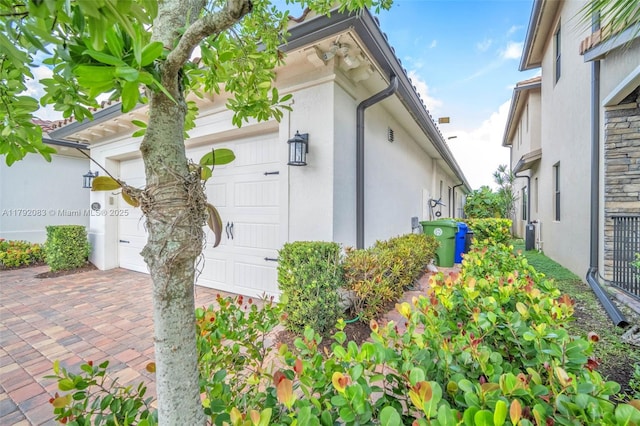 view of side of property featuring an attached garage and stucco siding