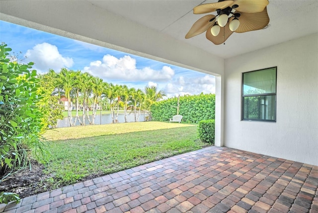 view of patio with a water view and a ceiling fan