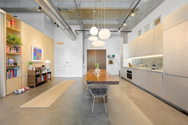 kitchen with open shelves, finished concrete flooring, a towering ceiling, oven, and a sink