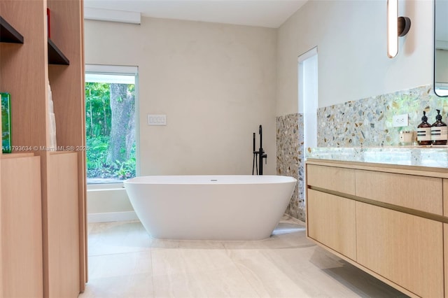full bathroom with a freestanding bath, tile patterned flooring, and vanity