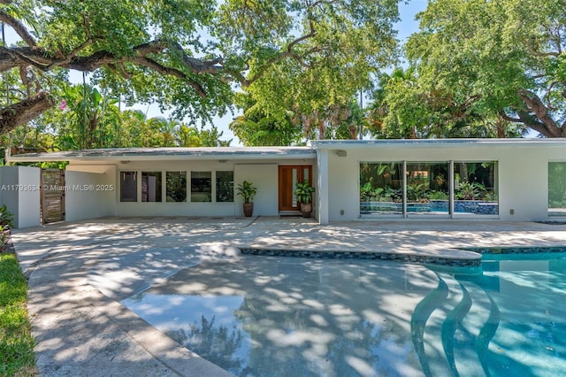 exterior space featuring an outdoor pool, a patio area, and stucco siding