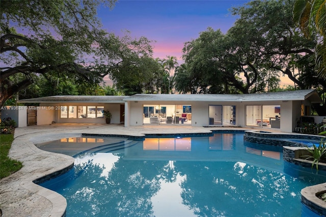 1075 NE 99th St, Miami Shores, FL 33138 - pool at dusk featuring a patio area and a pool with connected hot tub