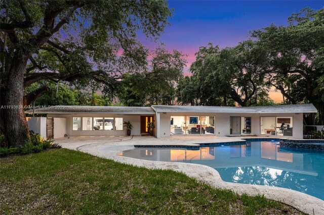 1075 NE 99th St, Miami Shores, FL 33138 - pool at dusk featuring a patio area, an outdoor pool, and a yard