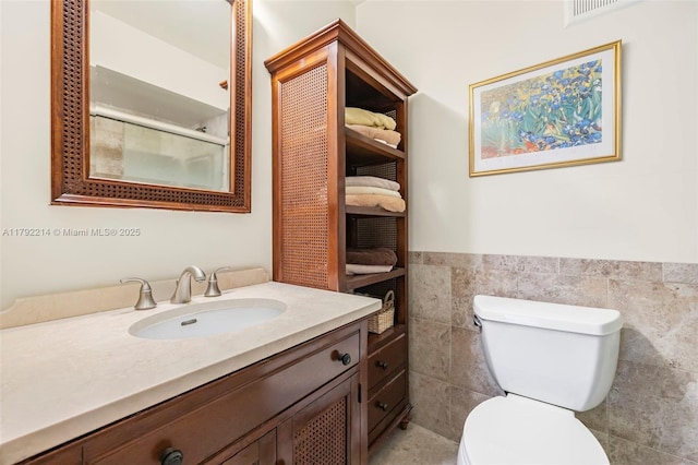 10761 SW 113th Pl Unit 102D, Miami, FL 33176 - bathroom with vanity, visible vents, toilet, tile walls, and a wainscoted wall