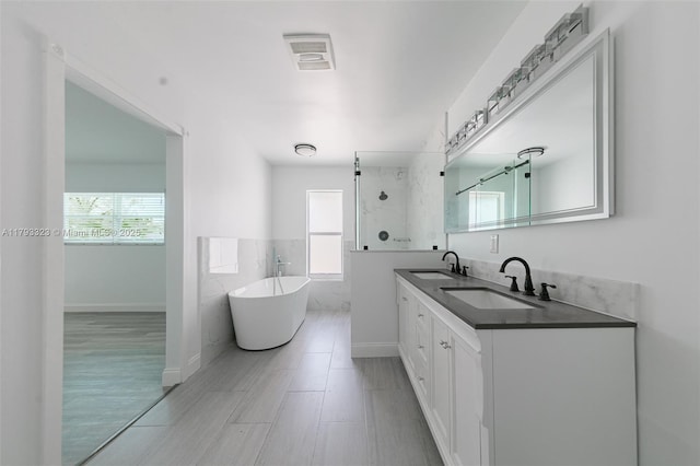 3401 SW 141st Ave, Miramar, FL 33027 - bathroom featuring a soaking tub, a walk in shower, tile walls, double vanity, and a wainscoted wall