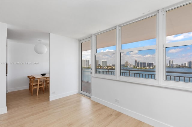 unfurnished room with baseboards, light wood finished floors, and a view of city