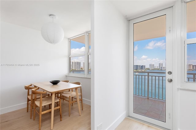 dining room with baseboards, a water view, and wood finished floors