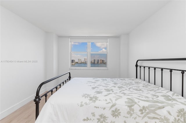 bedroom with a view of city, baseboards, and light wood-type flooring