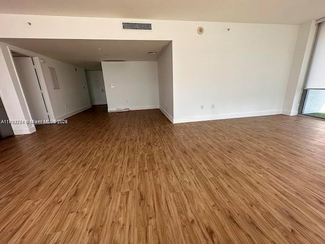 empty room featuring baseboards, wood finished floors, and visible vents