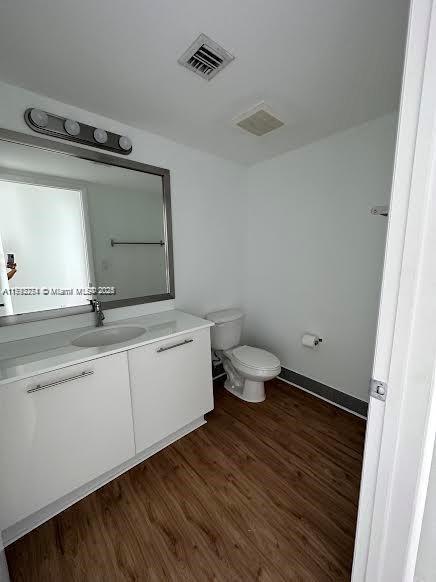 bathroom featuring toilet, visible vents, wood finished floors, and vanity