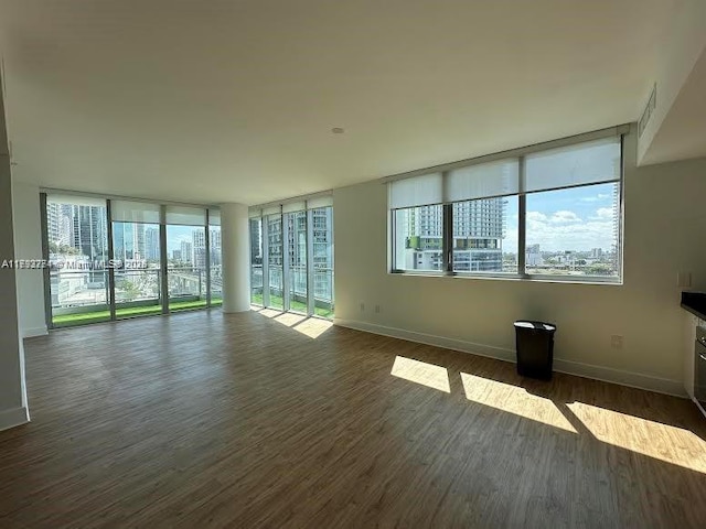 unfurnished living room featuring a healthy amount of sunlight, baseboards, and dark wood-type flooring