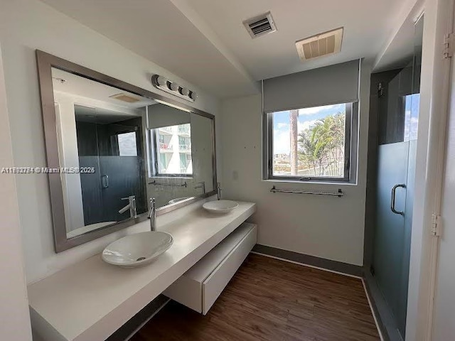 full bath with a sink, baseboards, wood finished floors, and visible vents