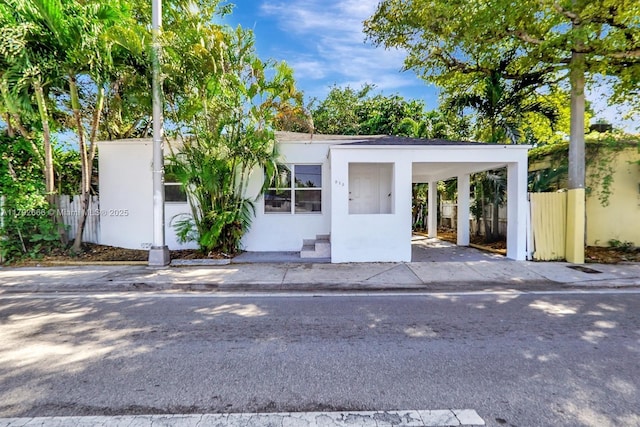 view of front of property with fence, a carport, and stucco siding