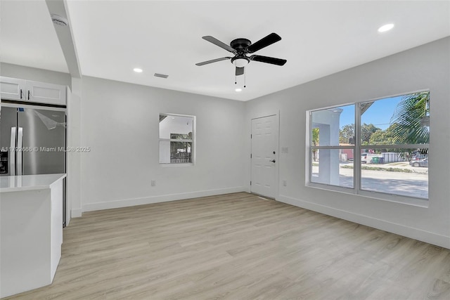 unfurnished living room featuring visible vents, light wood-style flooring, ceiling fan, and baseboards
