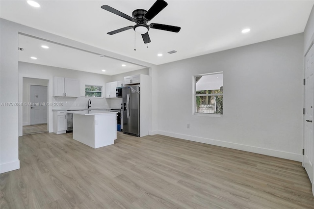 kitchen featuring a kitchen island, ceiling fan, light wood-type flooring, light countertops, and stainless steel appliances
