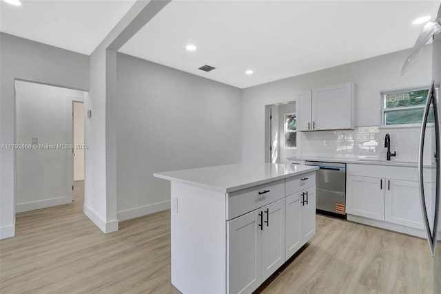 kitchen with stainless steel dishwasher, visible vents, a sink, and light wood-style floors