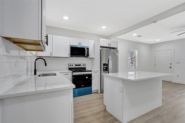kitchen with light wood-type flooring, a sink, decorative backsplash, and appliances with stainless steel finishes