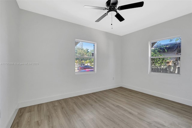 empty room with a healthy amount of sunlight, baseboards, and light wood-type flooring