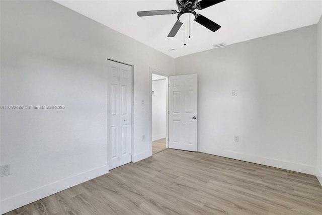 unfurnished bedroom featuring visible vents, a closet, light wood-style floors, baseboards, and a ceiling fan