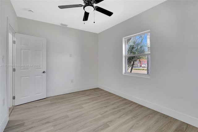 spare room with baseboards, a ceiling fan, light wood-style floors, and visible vents