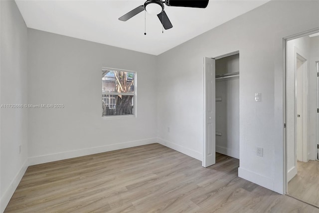 unfurnished bedroom featuring baseboards, ceiling fan, a closet, and light wood finished floors