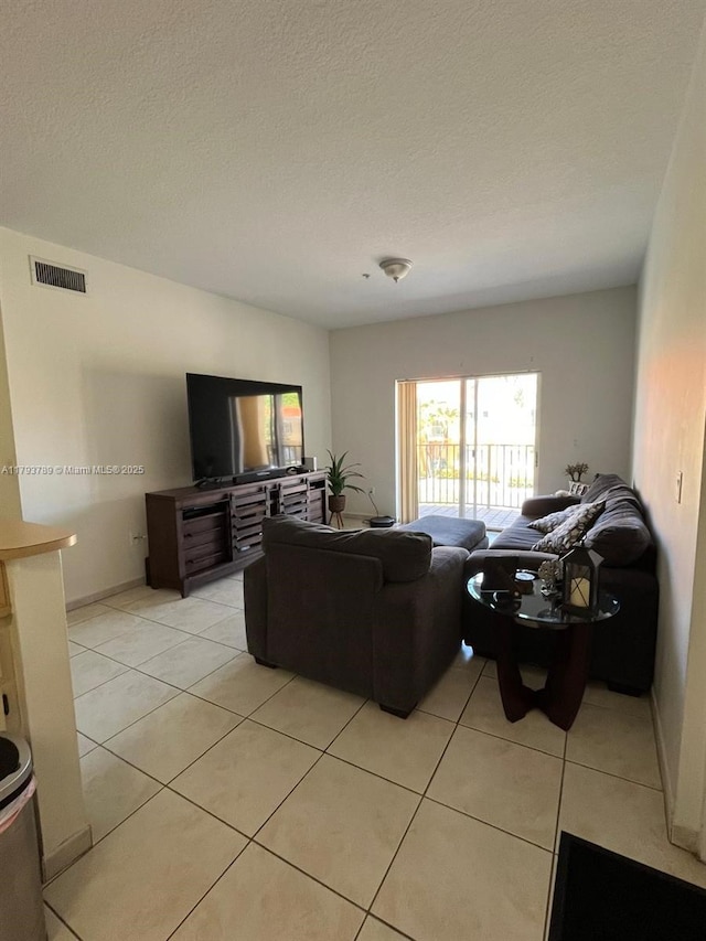 living area with light tile patterned floors, a textured ceiling, and visible vents