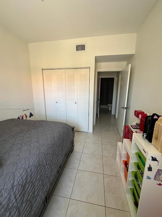 bedroom featuring light tile patterned flooring, visible vents, and a closet