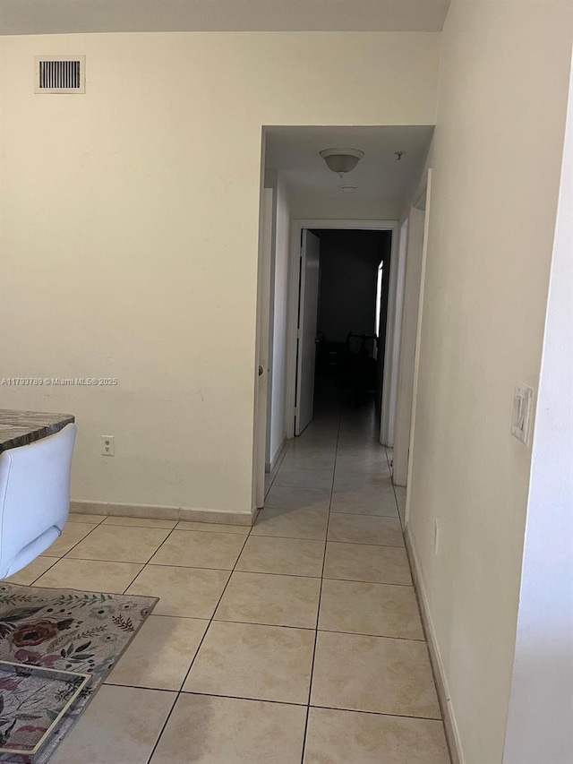 hallway featuring light tile patterned flooring, baseboards, and visible vents