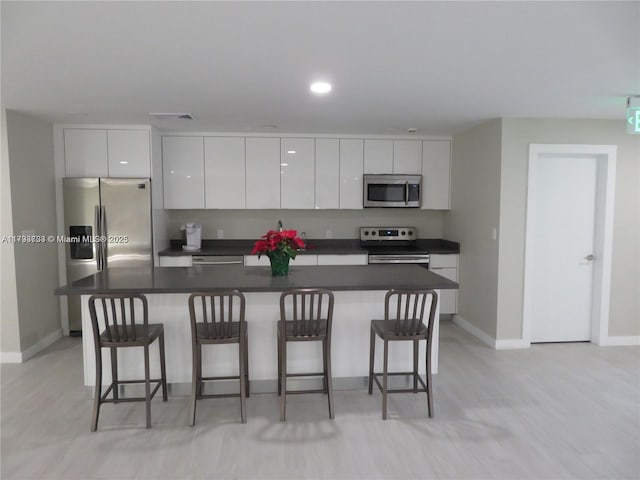 8005 SW 107th Ave Unit 118, Miami, FL 33173 - kitchen featuring a kitchen bar, modern cabinets, baseboards, stainless steel appliances, and white cabinetry
