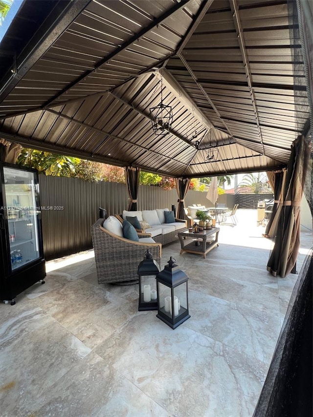 view of patio featuring a gazebo, an outdoor living space, and fence