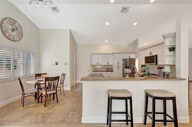 5133 N Springs Way, Coral Springs, FL 33076 - kitchen with open shelves, a peninsula, a breakfast bar, tasteful backsplash, and stainless steel appliances