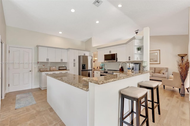5133 N Springs Way, Coral Springs, FL 33076 - kitchen with visible vents, open shelves, a peninsula, light stone counters, and appliances with stainless steel finishes