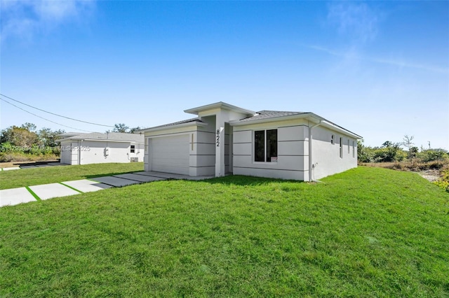 932 Alcalde St E, Lehigh Acres, FL 33974 - view of front of home with a garage, stucco siding, and a front lawn