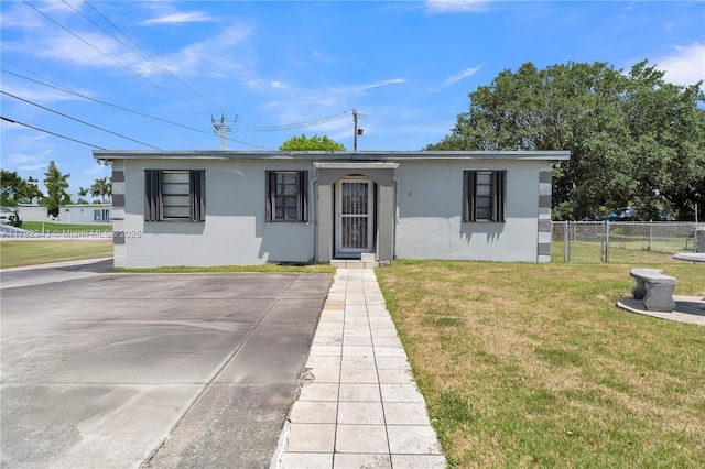 ranch-style house with stucco siding, fence, and a front lawn