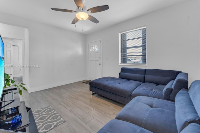 living area featuring baseboards, a ceiling fan, and wood finished floors