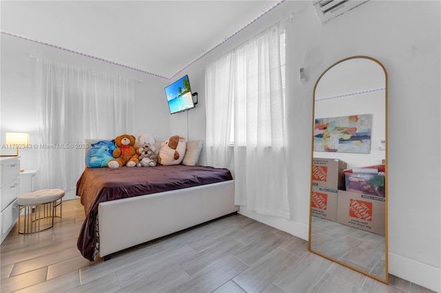 bedroom featuring multiple windows, a wall mounted AC, and wood finished floors