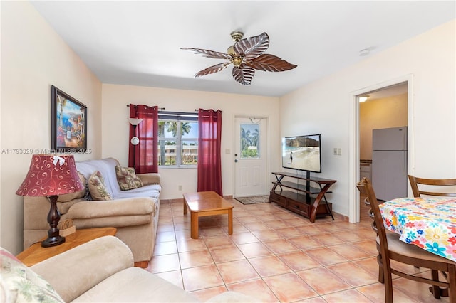 living area with a ceiling fan, baseboards, and light tile patterned floors