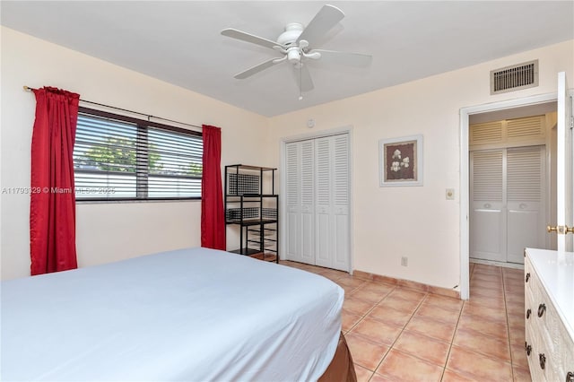 bedroom featuring a ceiling fan, baseboards, light tile patterned floors, visible vents, and a closet