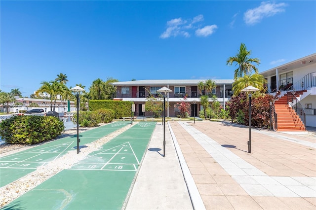 view of property's community featuring stairs and shuffleboard