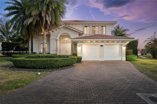 mediterranean / spanish home with decorative driveway, stucco siding, a tile roof, and fence