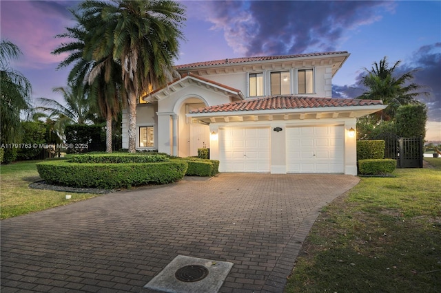 mediterranean / spanish home with a tiled roof, stucco siding, and decorative driveway