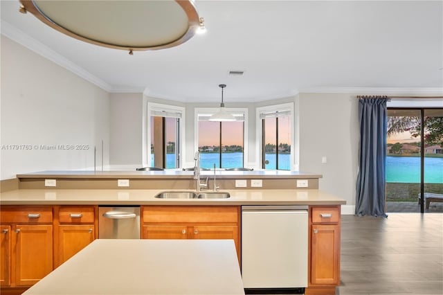 kitchen featuring a sink, dishwasher, light countertops, wood finished floors, and visible vents